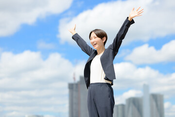 青空の下で万歳をする女性