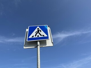 Pedestrian crossing sign with blue sky and clouds in the background