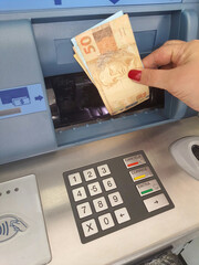 Withdrawing money from ATM, woman's hand taking money