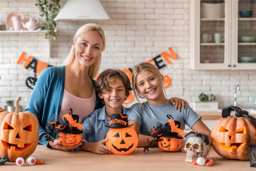 Happy caucasian mother with her little children kids son and daughter making cutting decorating...