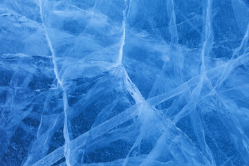 Beautiful winter natural blue ice texture of surface of frozen Baikal Lake in cold day. Nature abstract pattern of white cracks. Winter seasonal background, mock up, flat lay, blank, top view