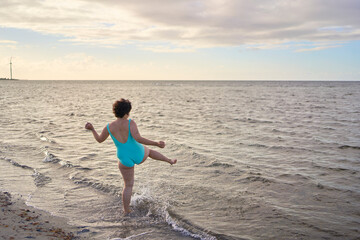 a young plus-size woman is engaged in winter swimming and warming up by the sea