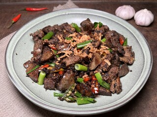Stir fry spicy chicken lever served with crispy fried onion and spring onion.