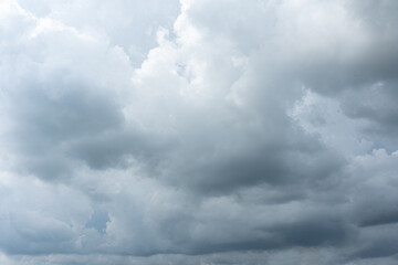 Dramatic cloudscape of fluffy white clouds against a deep blue sky, illuminated by the warm light of the setting sun