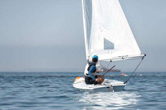 Young man sailing dinghy alone in the sea on a sunny day