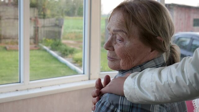 Child putting hand on shoulder of sad elderly woman. Support and care in family. Care for old in a nursing home. Meeting of relatives and friends. A helping hand. Empathy for patients. Look at window