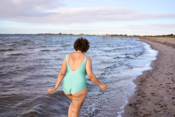 a young plus-size woman is engaged in winter swimming and warming up by the sea