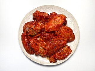 Marinated spicy chicken wings on a plate on a white background, isolated. Top view. Copy space. Semifinished. Fast cooking. Raw marinated chicken meat.