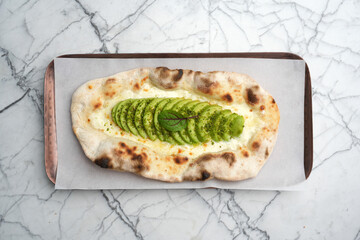 Vegetarian pizza with cheese, avocado and pita bread, top view