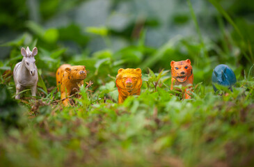 A collection of wild animal figurines, plastic toy miniatures in the natural environment. Tiger, Leopard, Lion, Zebra, Rhino, Bear, Giraffe.
