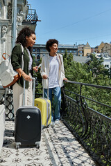 Two happy women share a moment on their hostel balcony, ready to explore the vibrant city around...