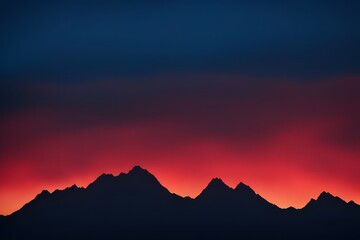 Obraz premium Silhouetted mountain peaks with a sky transitioning from fiery red to cool blue, AI Generated