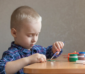 portrait of a boy painting with colored paints.  little child playing with paints