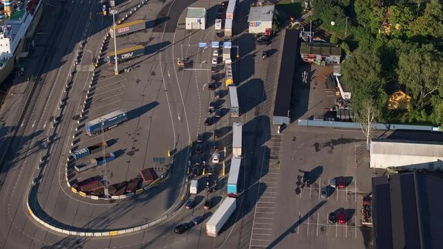 Aerial views showcase semi trailer trucks waiting to board a ferry at Turku's port in Finland on a sunny summer morning, highlighting the vibrant transportation and logistics activity