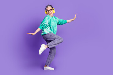 Obraz premium Full size photo of pretty retired female earphones dance have fun wear trendy green outfit isolated on violet color background