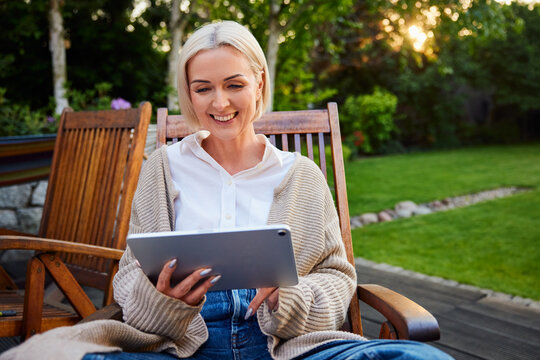 Mature woman relaxing outdoors using digital tablet in garden