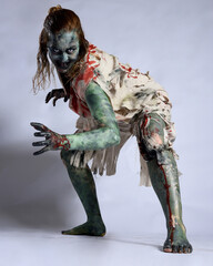 portrait of scary female model wearing spooky halloween costume, ripped clothes and fake blood like...