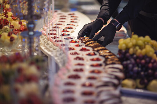 Catering food, food wedding celebration. caterer arranges array of appetizers on a serving table, showcasing a variety of fresh and delicious options. hands of a waiter prepare food for a buffet table