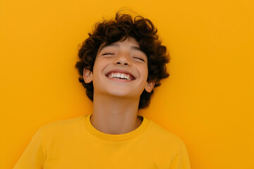 Joyful boy with eyes closed and a big smile, radiating happiness and positivity. His curly hair frames his face as he looks up with bliss