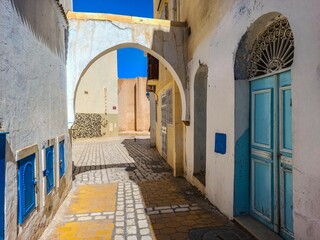 One of the streets of the old Tunisian cities, where the distinctive Tunisian Arab architecture is evident, with the beautiful colours of its doors and windows and its narrow streets.