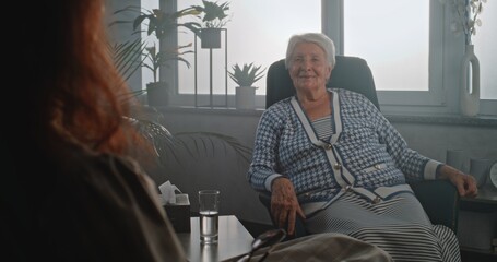 Senior woman at appointment with psychologist or psychotherapist. Elderly client sitting in chair,...
