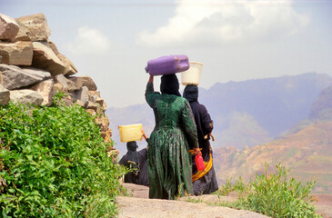 Women in traditional Yemen clothes on their way home carrying water from a  well near the Yemeni town of Marib