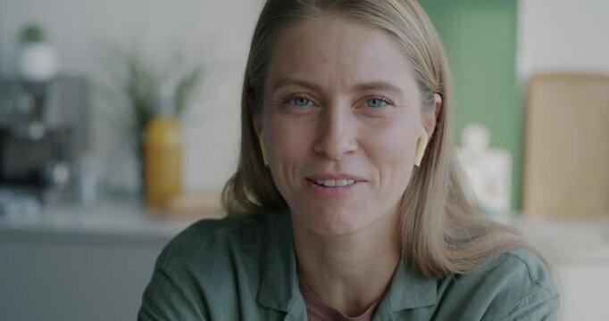 Portrait of young woman talking looking at camera making online video call in kitchen at home. Virtual meeting and distance communication concept.