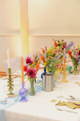 An elegant wedding table setup with colorful floral arrangements and various candles creating a festive atmosphere.