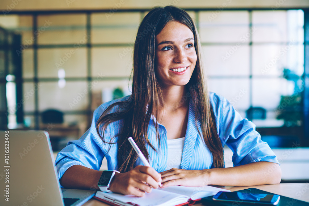 Poster smiling successful woman with netbook enjoying planning process while sitting at desktop with modern