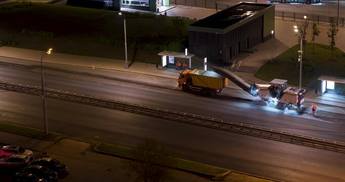 Time lapse of working cold milling machine at the night city highway with hard traffic. Aerial view