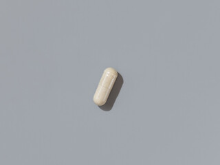 Beige Medical capsule on grey top view, hard shadows. Taking dietary supplements