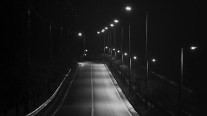 A quiet nighttime road illuminated by streetlights in a serene, low-traffic area during the late...