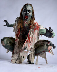 portrait of scary female model wearing spooky halloween costume, ripped clothes and fake blood like...
