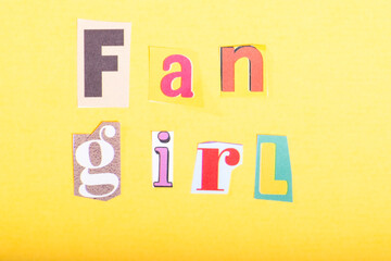Phrase Fan Girl spelled in cut out newspaper style typography, isolated on yellow background.