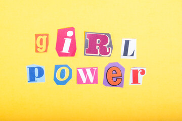 Phrase Girl Power spelled in cut out newspaper style typography, isolated on yellow background.