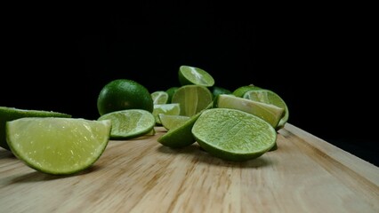 Close-up, a vibrant slice of fresh lime rests upon a rustic wooden cutting board, exuding freshness and vitality. The translucent membranes of the green lime slice placed on cutting board. Comestible.