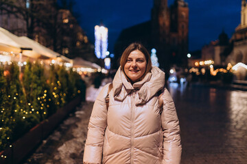 Happy woman posing near St. Mary's Basilica at the main square in Krakow. Winter holidays time