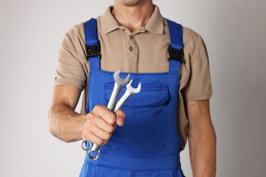 Auto mechanic with wrenches on light grey background, closeup