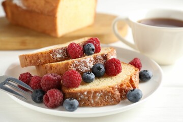 Freshly baked sponge cake, raspberries and blueberries on white wooden table, closeup