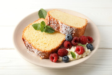Freshly baked sponge cake, whipped cream, berries and mint on white wooden table