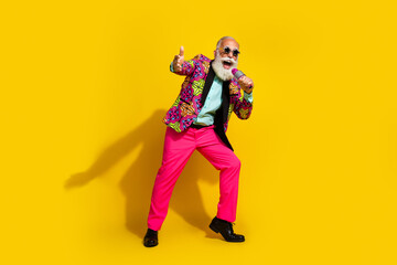 Full body portrait of eccentric cheerful man sing microphone wear vibrant outfit isolated on yellow color background