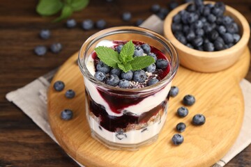 Tasty trifle dessert. Blueberries, sponge cake and whipped cream in glass on wooden table