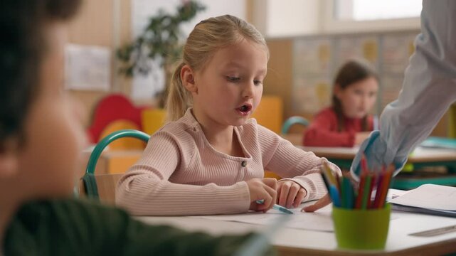 Elementary primary education studying in school multiracial pupils multiethnic children kids African American in classroom writing test exam little Caucasian girl difficult confused teacher help write