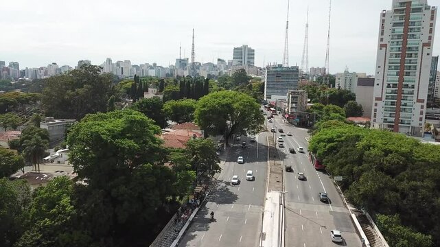 Drone view of Sumare Avenue with a mix of traffic, trees, and urban structures