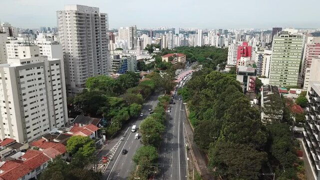 Drone shot of Sumare Avenue in S&atilde;o Paulo with buildings, trees, and light traffic