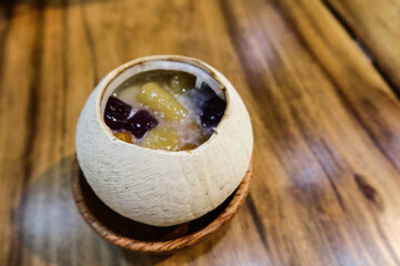 Close up of Chinese sweet soup dessert steamed milk egg white pudding with yam and sweet potato taro ball in the coconut