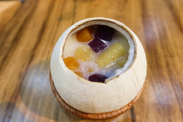 Close up of Chinese sweet soup dessert steamed milk egg white pudding with yam and sweet potato taro ball in the coconut