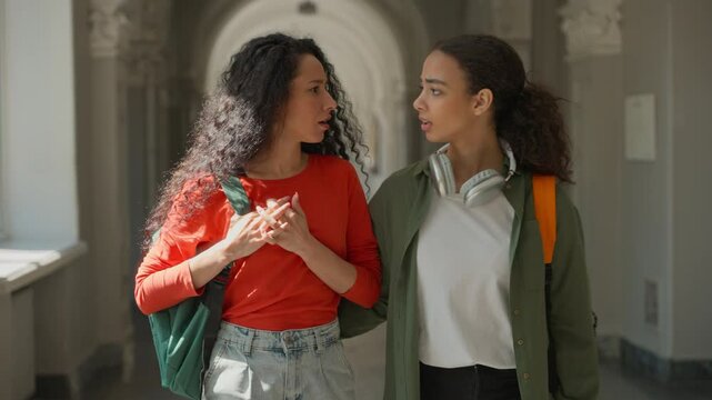 Two friends people students girls multiracial females multiethnic women Caucasian Hispanic Latina classmates walking go in school college university girl feel stomach pain abdominal menstrual ache