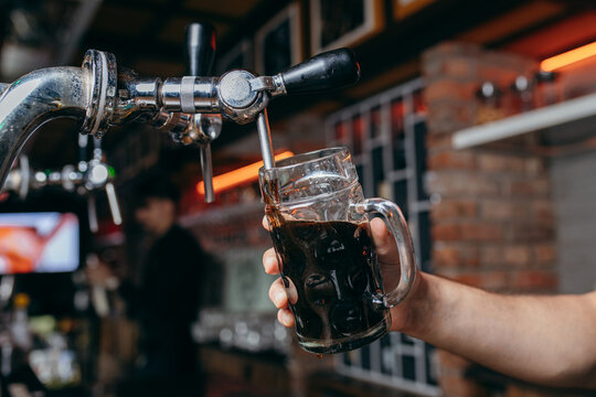 Bartender pouring beer at the bar. Close up hands	
