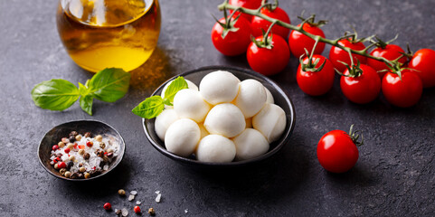 Mozzarella cheese balls with fresh tomatoes and basil. Dark background. Close up.